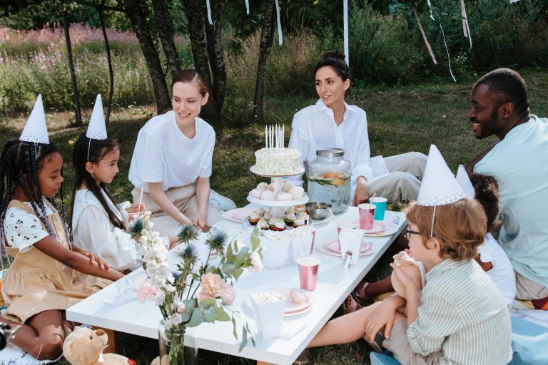 A diverse family enjoying a garden party with kids and a cake outdoors.