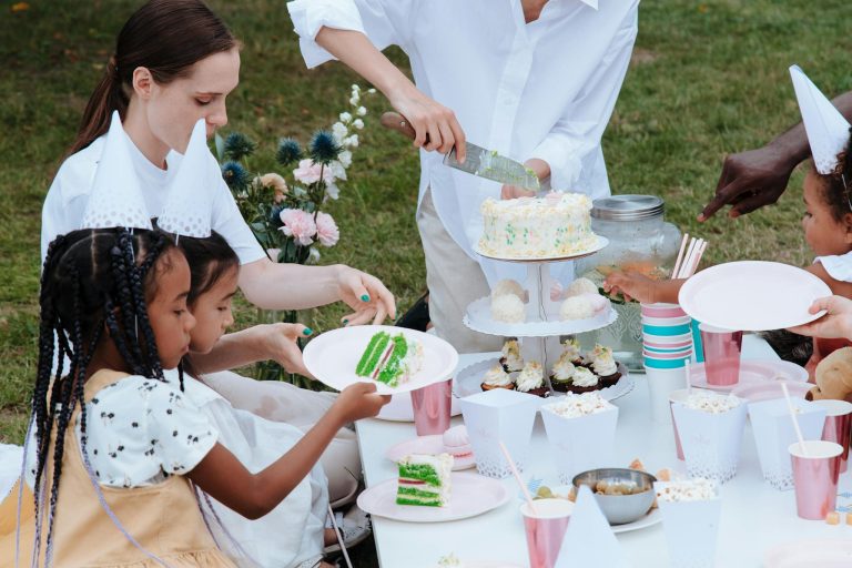 A vibrant outdoor birthday party with kids enjoying cake and snacks. Multiracial celebration.