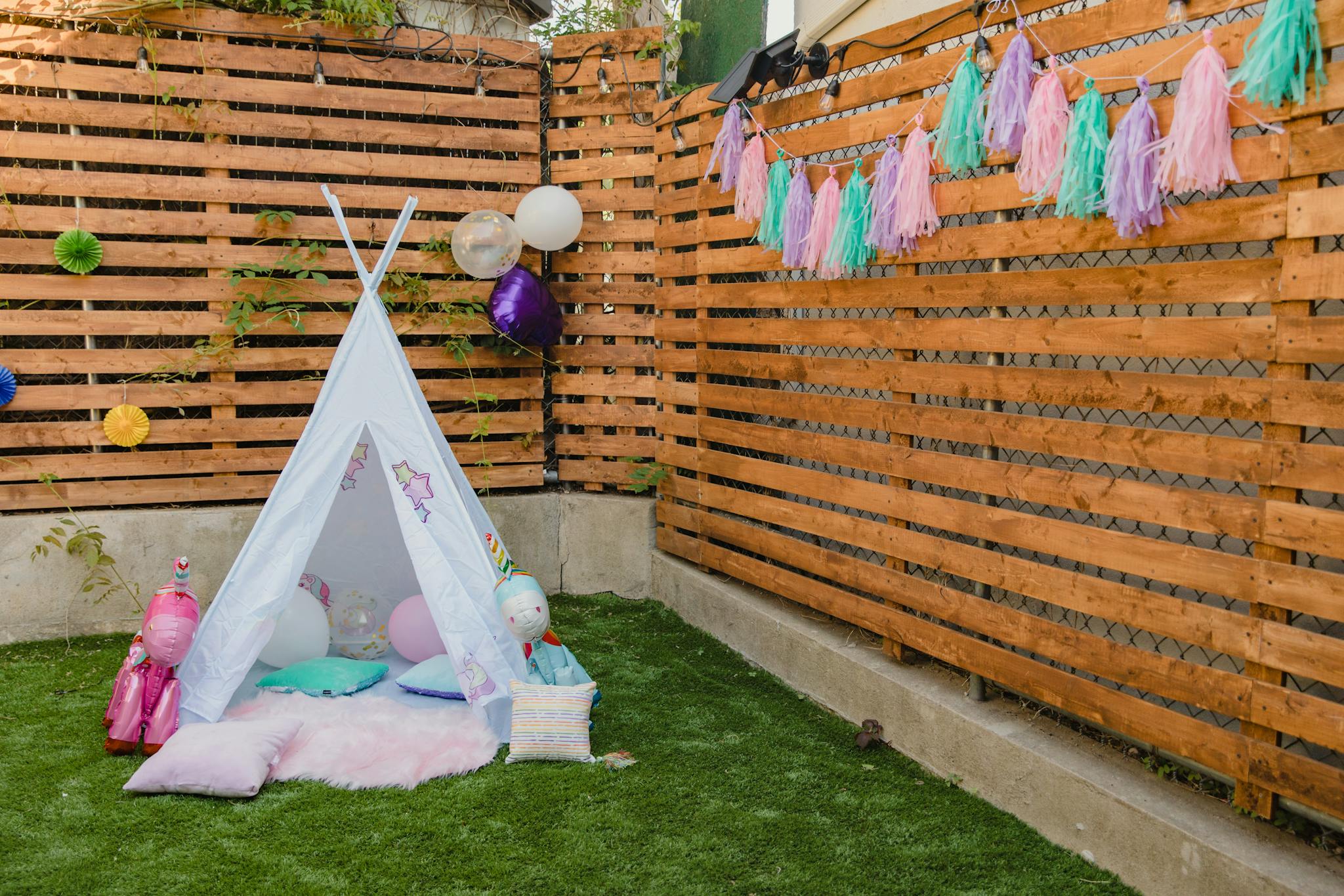 Charming children's party setup with colorful decorations and a tent in a garden setting.