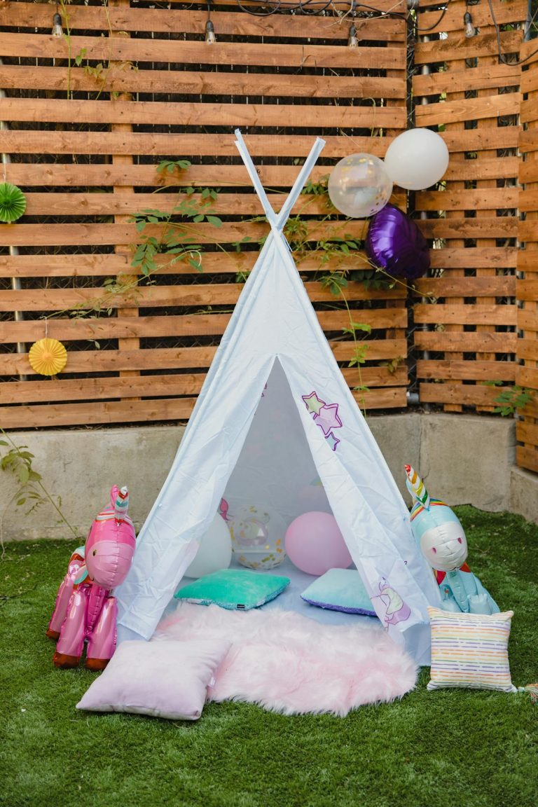 Whimsical outdoor teepee decorated for a kids' party with colorful balloons and plush toys.